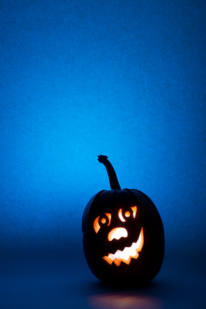 Halloween pumpkin, silhouette of funny face on blue background.の写真素材