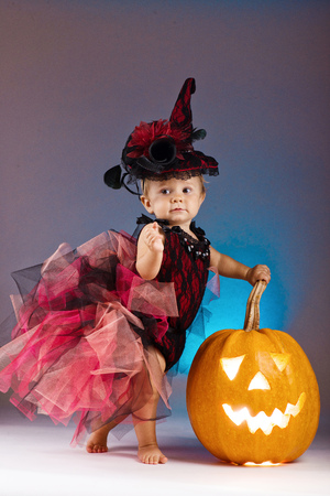 Little witch girl child laughing among pumpkins and candles.の写真素材