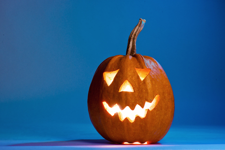 Halloween pumpkin, silhouette of funny face on blue backgroundの写真素材