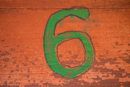 Green number six on a brown wall texture for a background. Old peeling paint.の写真素材