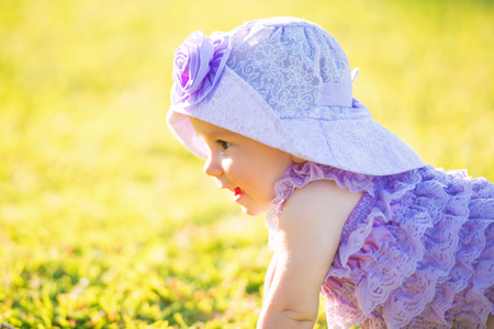 Portrait of a happy girl on vacation. A girl in purple is sitting on the lawnの写真素材