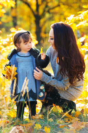 Little girl and her mother playing in the autumn parkの写真素材