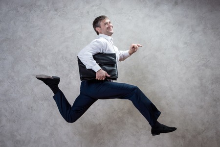 running businessman with briefcase on gray background.の写真素材