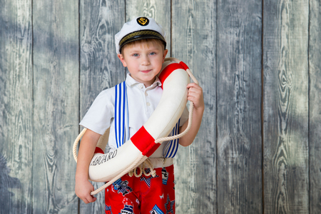 Smiling boy in captain's cap holds in his hands a lifebuoy.の写真素材