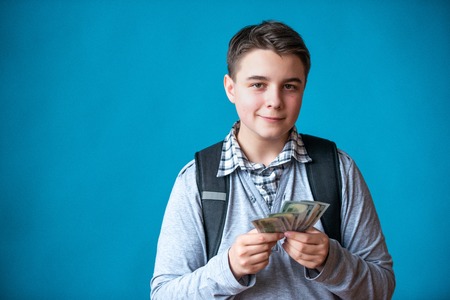 Cash loan, first easy money and spending money. The boy teenager holds in the hands the earned money. Earnings or winnings online.の写真素材