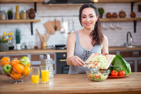 Pretty young woman cutting vegetables salad in the kitchen.の写真素材