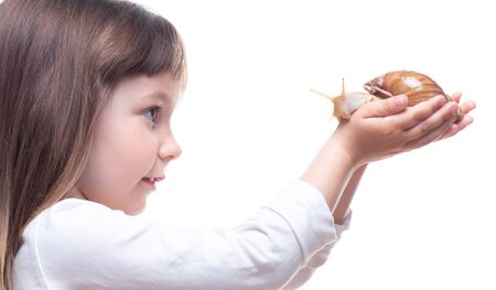 Attractive little girl is holding a Akhatina snail. Isolated on white background. Close up. Concept of youth and beauty skin, facial rejuvenation.の写真素材