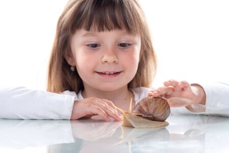 Cute little girl and Akhatina snail. Close up. Concept of youth and beauty skin, facial rejuvenation.の写真素材