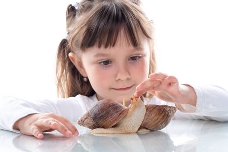 Cute little girl and Akhatina snail. Close up. Concept of youth and beauty skin, facial rejuvenation.の写真素材