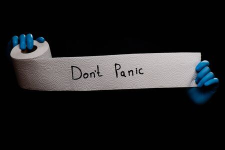 Panic buying Covid-19 Coronavirus outbreak concept. Roll of toilet paper with inscription Don't panic on black background.の写真素材