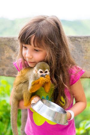 A girl feeds a saimiri monkey in the Dominican Republic. Excursion to Monkey Land, Monkey Park. high quality photoの写真素材