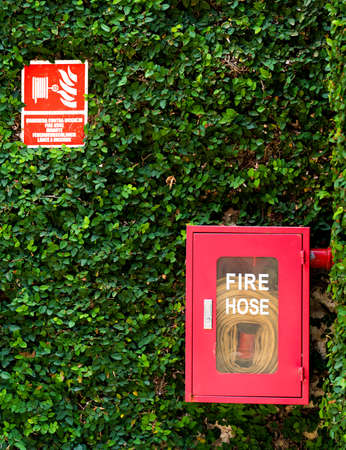 Red fire hose hangs on a stone wall in an exotic hotel. Fire extinguishers and security. high quality photoの写真素材