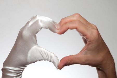 White elegant heart shaped female glove and  man's hand isolated on white backgroundの写真素材