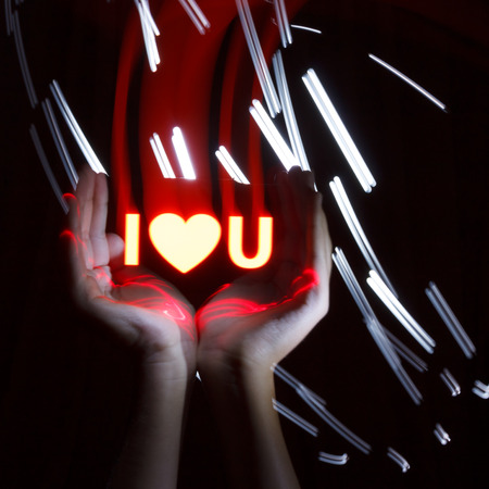 Light Painting Photography. Freezelight photo. Hands holding a red glowing massage with freezelight effect.の写真素材