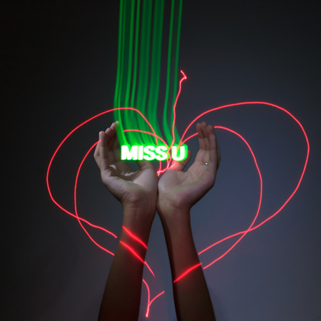 Light Painting Photography. Freezelight photo. Hands holding a green glowing message with freezelight effect.の写真素材