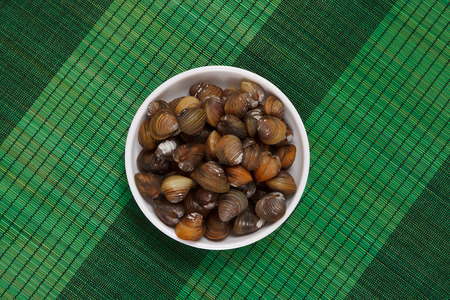 A top view of a bowl with uncooked mussels on a green matの写真素材