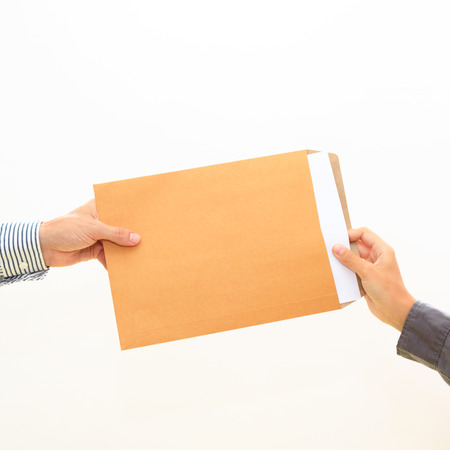 woman's hand passes a yellow envelope to male hand on white background view 3の写真素材