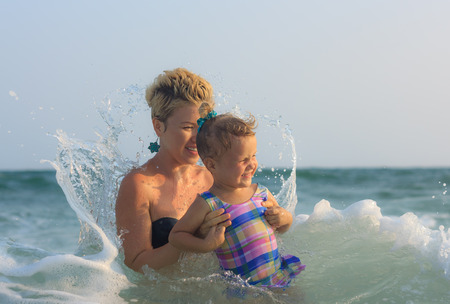Mother and daughter swimming together in big sea waves view 1の写真素材