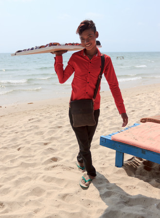 SIHANOUKVILLE, CAMBODIA -  MARCH 03, 2015: unidentified beach seller boy of sunglasses on coastlineのeditorial素材