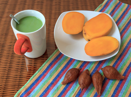 Cup of green tea with milk and with tropical fruits on a glass surfaceの写真素材