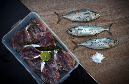Fresh tuna chopped for soaking in salt, pepper and herbs on wooden background, horizontal view