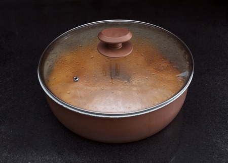 Closeup of a chicken and potato pie in casserole with lid on against black marble backgroundの写真素材