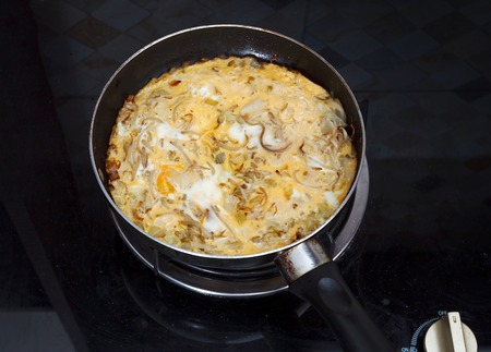 Omelette with fried eggs, sprouts and onions, frying process in pan