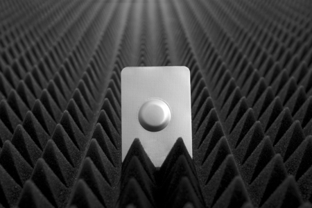One medical pill in blister pack against black bumpy background view 3