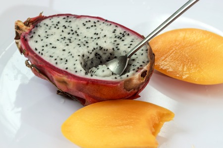 Dragon fruit and mango sliced on white plate with spoon, selective focusの写真素材