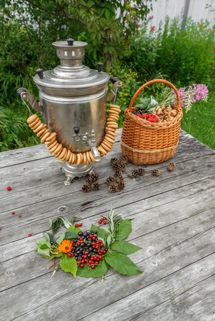 russian samovar on a rustic wooden table with berries and flowers in the garden front viewの写真素材