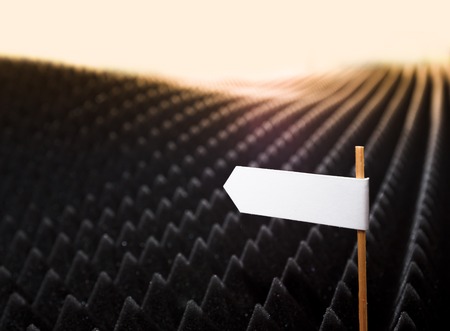 blank white directional sign on bumpy black background horizontal viewの写真素材