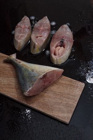 Fresh sea fish sliced and ready for cooking on wooden board  on black marble table laid with ice