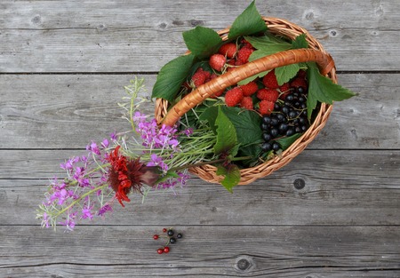 basket with berries and flowers on a rustic wooden table in the garden top viewの写真素材