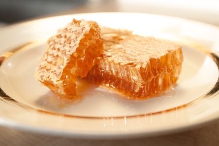 Photo with seletive focus of stacks of honey comb on a plate on wooden table, horizontal viewの写真素材