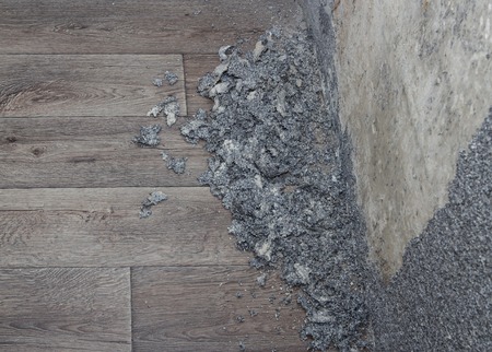 Dismantle process of grey wall stucco with crushed pieces on floorの写真素材