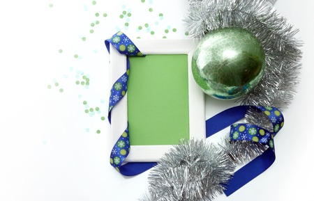 New Year and Christmas greeting card template made of white frame and green card with blue ribbon, green ball, silver tinsel and confetti, horizontal viewの写真素材