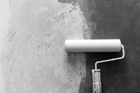 Closeup of paint roller applying paint on white wall, home improvements, grey scale photo, horizontal viewの写真素材