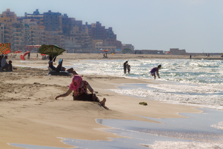 ALEXANDRIA, EGYPT - OCTOBER 13, 2014: Unidentified local people having rest on the local beach on a sunny summer day on October 13, 2014 in Alexandria, Egypt.のeditorial素材
