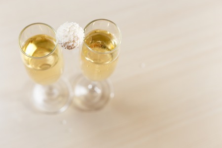 Selective focus photo of two glasses of sparkling wine and coconut chip candy on top of both with copy space, horizontal top view, connection and celebration conceptの写真素材