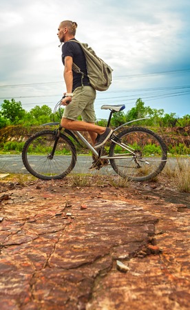 Young  man riding bicycle in mountainous country on sunny summer dayの写真素材