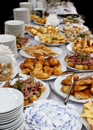 Selective focus photo, catering banquet table with baked food snacks, sandwiches, cakes, cups and...