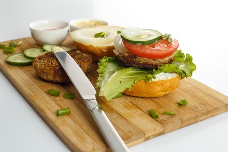 Cooking process of a sandwich burger, ingredients on wooden cutting board on wooden table against...