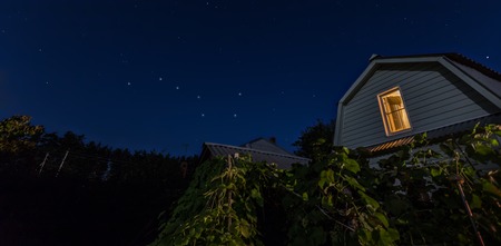 View of night sky stars of Big Dipper at villiage with house and trees at the foreground, horizontal...