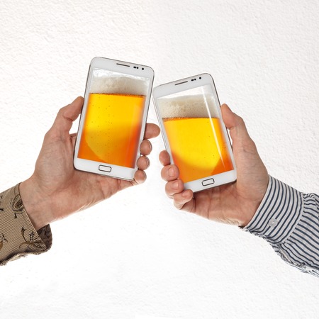 Two male hands in shirts hold smart phones with beer against white background. Concept of online...