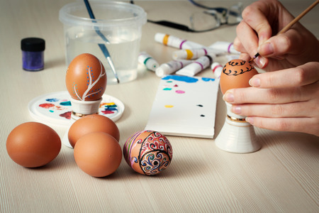 Female hands painting colorful Easter eggs at table, close upの写真素材