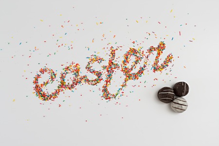 Easter lettering made from colorful baking sugar and chocolate candies over colorful background with copy space, horizontal top viewの写真素材