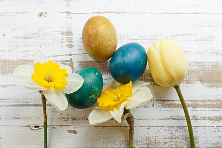 Bouquet of yellow spring tulip, daffodils and handmade colorful painted easter eggs against rustic...
