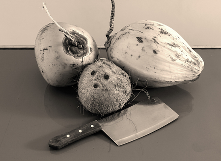 three different coconuts with machete on table horizontal view, greyscale photoの写真素材