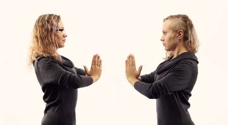 Part of series.Self talk concept. Young blond caucasian woman talking to herself, showing gestures. Double portrait from two different side views.の写真素材
