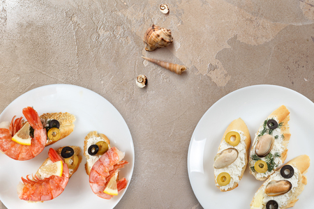 Beautiful snapshots of various italian sandwiches with seafood arranged on rustic wooden background with plates with food and seashells, with copy space, horizontal top view.の写真素材